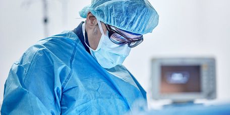 Arzt mit Maske und Haube operiert einen Herzpatienten